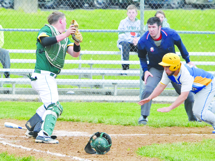 Manchester’s Mason Applegate, right, dives headfirst towards home plate as North Adams catcher Kenny Branch waits to make the tag.  Applegate was able to slide under the tag and score the first Greyhound run of the game, though it was the Devils who took the win 7-2.  Home plate umpire Matt Carson looks on to make the call.  Photo by Mark Carpenter