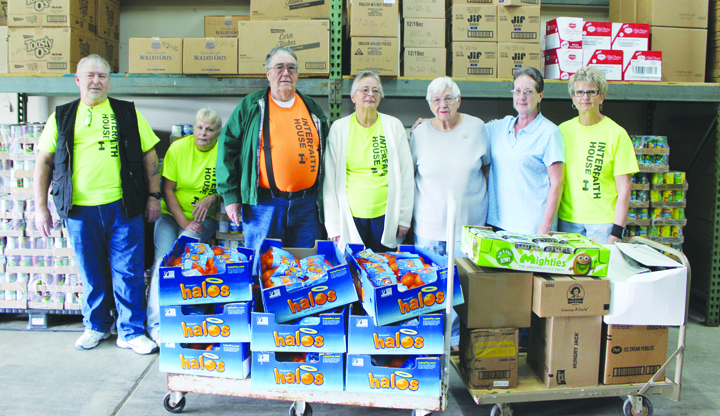 Interfaith House volunteers Robert Zink, Renee Velzkak, Gene Marshall, Carol Marshall, Joe-Ann Weber, Connie Henson, and Judy Robinson are standing behind two skids of groceries donated by New Life Ministries in Hillsboro.