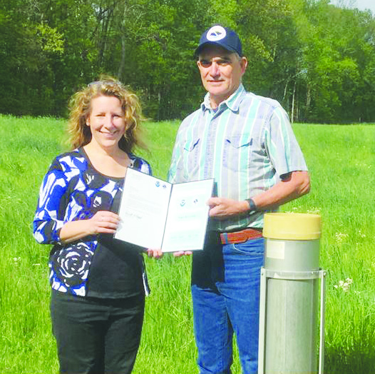 Long-time Adams County resident Roger Rhonemus was recently honored by the National Weather Service for his 35 years serving as a weather observer, presented his award here by NWS Service Hydrologist Julia-Dian-Reed. Provided photo.