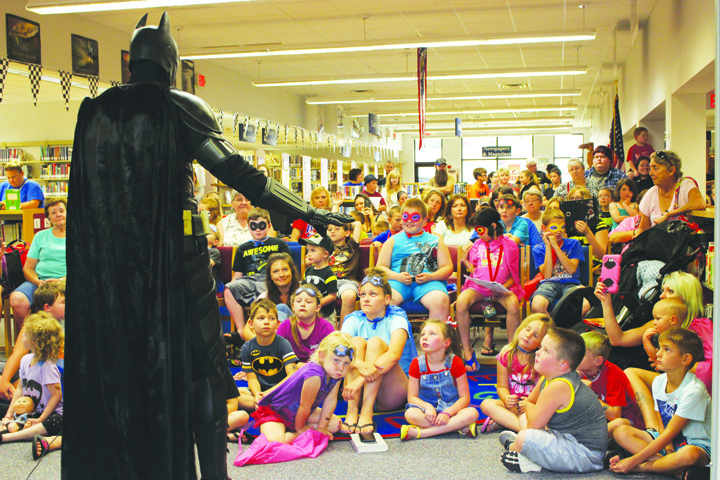 An enraptured audience of youngsters listens intently to the message of the Caped Crusader during his stop at the Peebles Library on July 6.