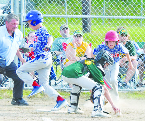 As North Adams catcher Christopher Young reaches for the loose ball, Peebles’ Mason Sims crosses the plate with the first run in the July 7 Class “C” Tournament championship game.