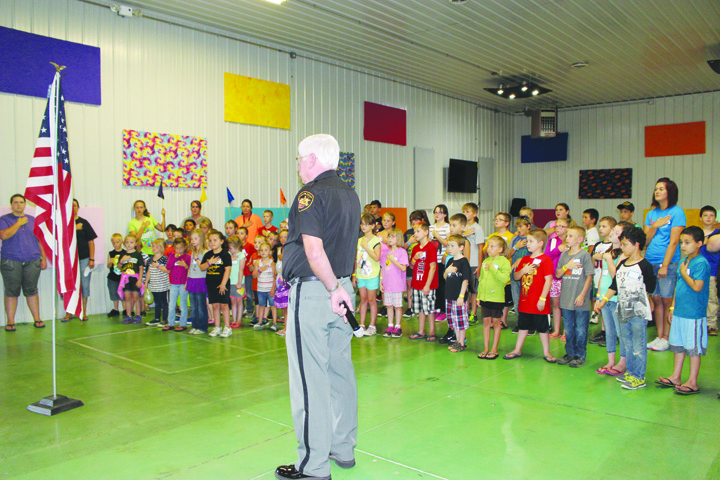 Adams County Sheriff Kimmy Rogers leads his group of Junior Deputy Boot Campers in Seaman in the Pledge of Allegiance.