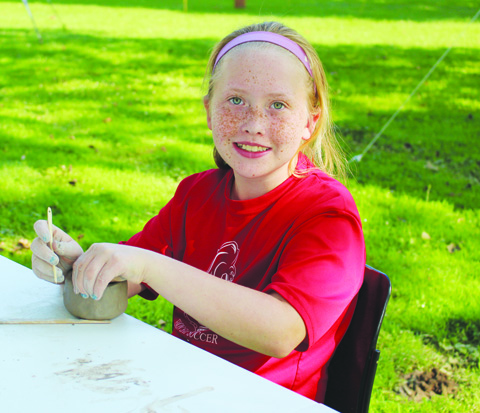 This young lady is all smiles as she creates pottery at the annual Serpent Mound Archaeology Day.