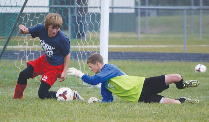 North Adams goalkeeper Cole Wagner reaches out to grab this ball before Peebles’ Weston Browning can turn a round and get a shot off in action from Saturday’s boys soccer game in Seaman, won by the Green Devils 8-1.