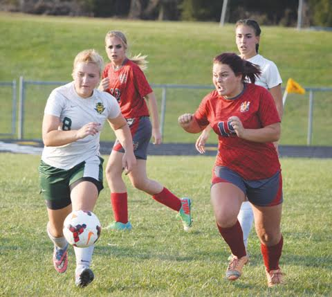 North Adams’ Jessica Woodall, left, chases the ball upfield with an intense Piketon defender on her heels in action from Tuesday’s Div. III sectional final, won by the Lady Devils 6-0. 
