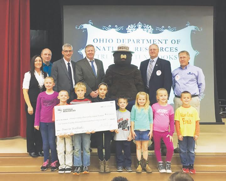 The Ohio Department of Natural Resources (ODNR) awarded more than $2 million to 16 rural Ohio school districts after selling timber from state forests as part of the Trees to Textbooks program. The Adams County Ohio Valley School District in Adams County received a check recently for $180,966 from Trees to Textbooks at Peebles Elementary School in Peebles. Pictured Back row,from left are: Amanda Lamb, Principal of Peebles Elementary School; John Lewis, Richard Seas, Superintendent of the Adams County Ohio Valley School District, James Zehringer, Director of ODNR, Robert Boyles, Ohio's State Forester, and Dale Egbert, Manager of Shawnee State Forest. Peebles Elementary School students are pictured holding the check. Front row, from left, Tatum Rigdon, Damon Holt, Steven Merrick, Chloe Taylor, Crew Wilson, Gabrielle Howard, Kendall Myers and Calen Vogler.